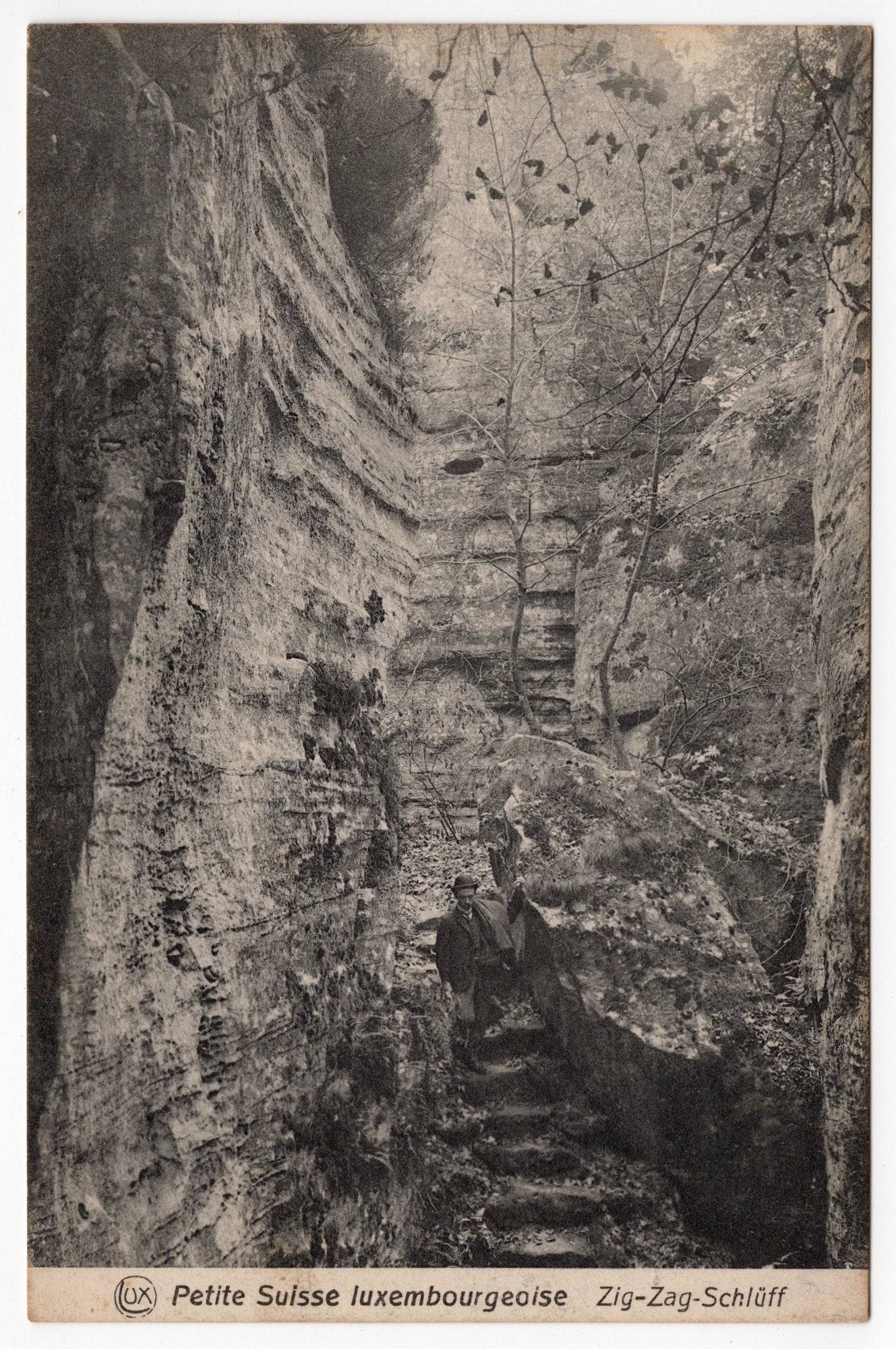 Zwart-wit ansichtkaart Zig-Zag-Schlüff Petite Suisse luxembourgeoise, wandelaar met stok in rotskloof, uitgave Schoren Luxemburg circa 1910