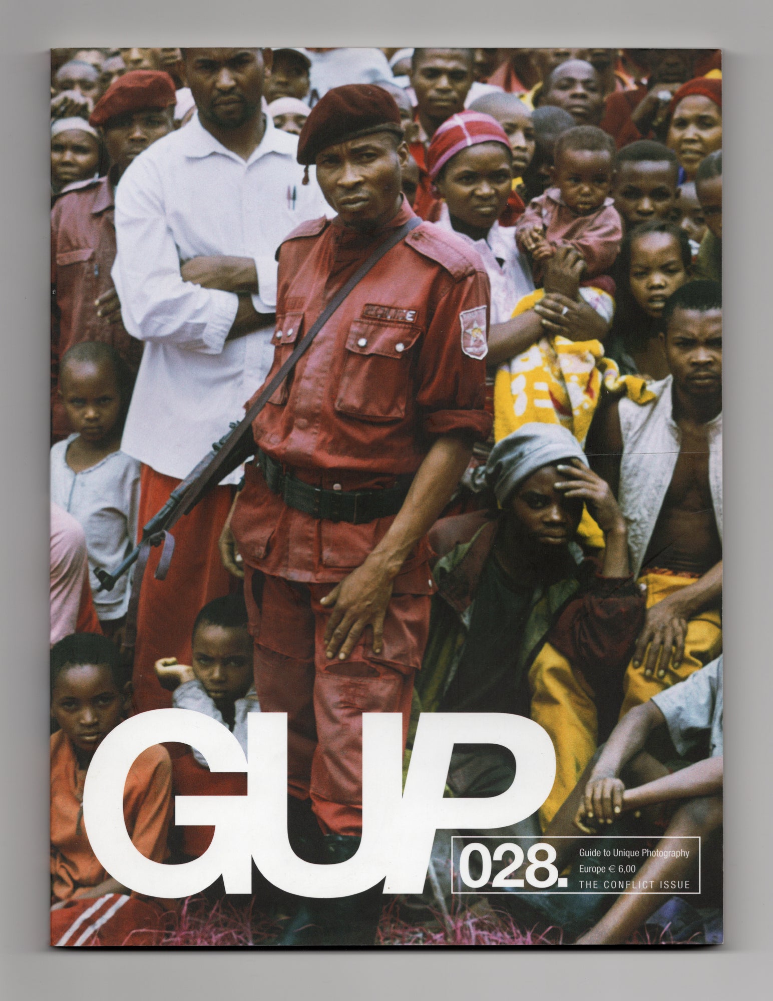 Cover GUP Magazine 028 The Conflict Issue uit februari 2011 met fotografie van politieagent in rood uniform met geweer in menigte van toeschouwers.