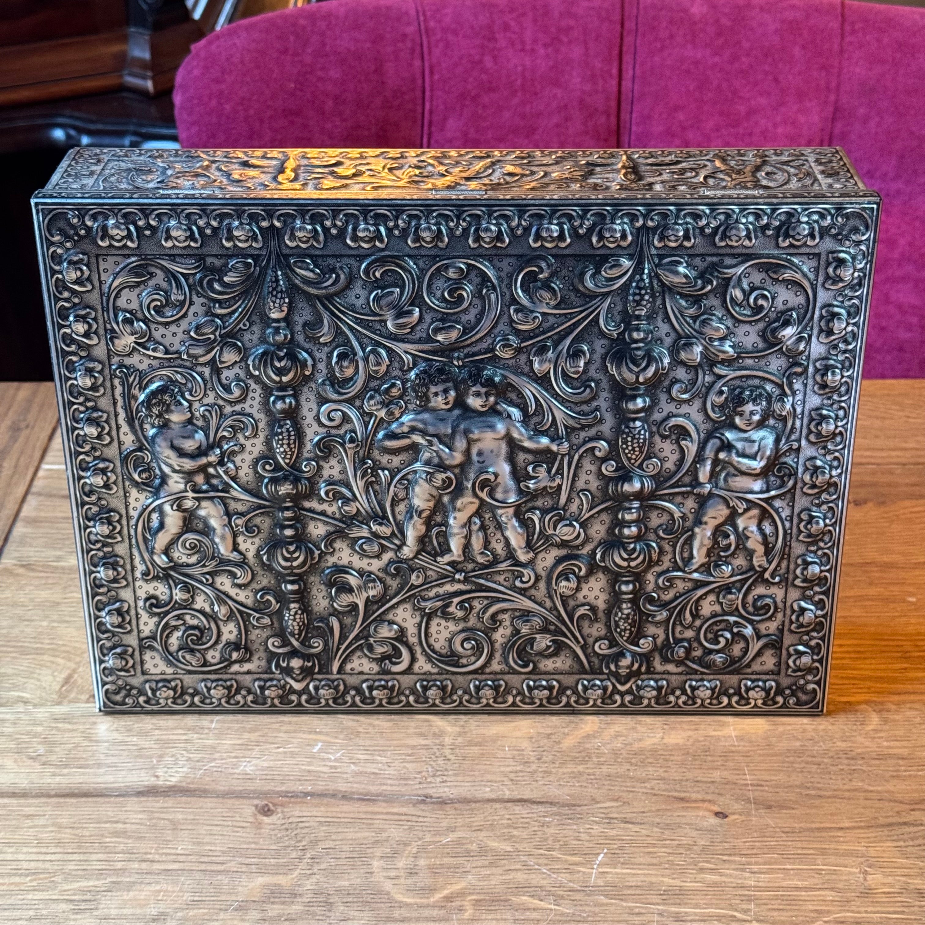 Large decorative storage tin with relief decoration of putti – Germany, ca. 1900–1930