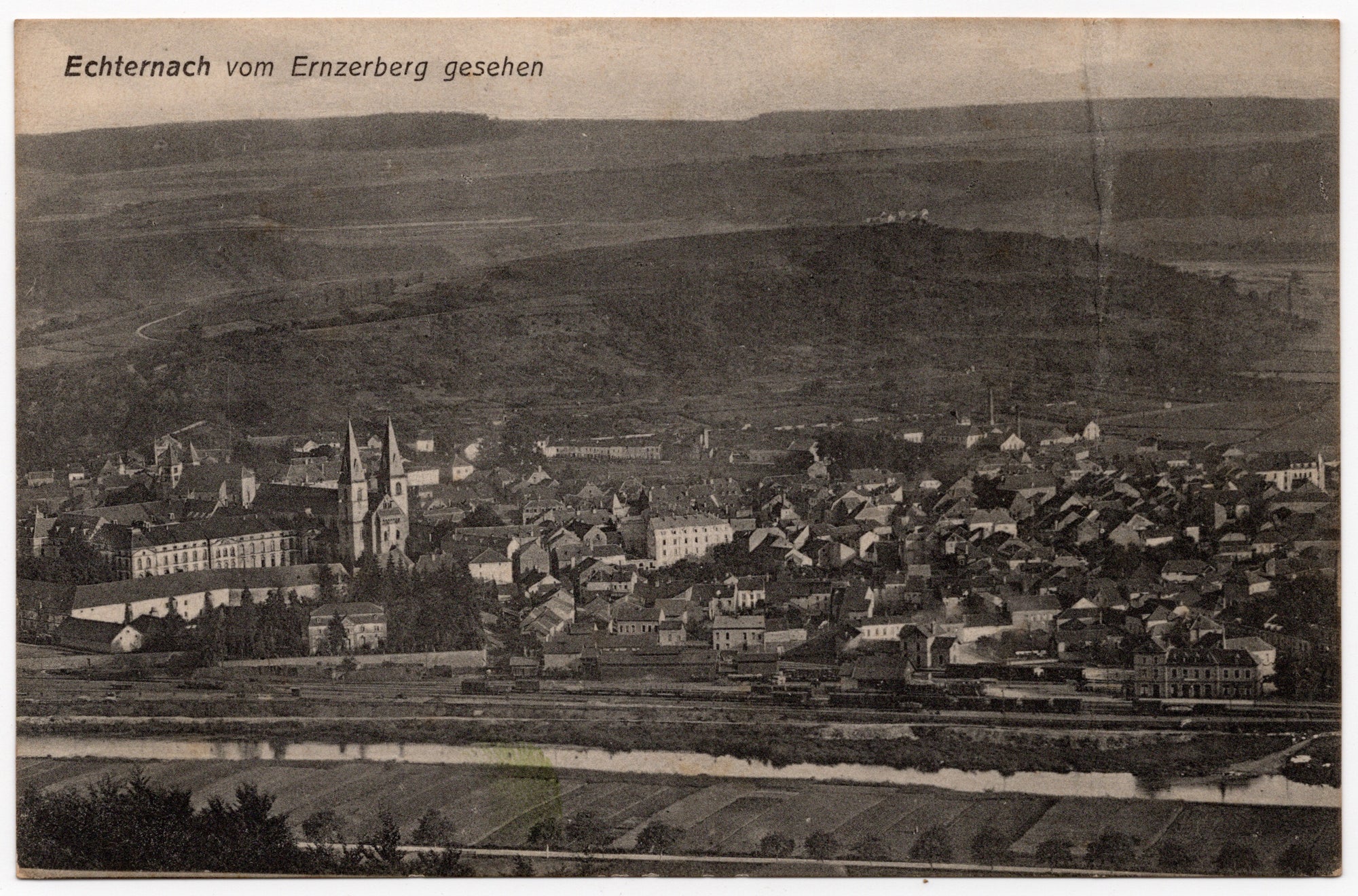 Luxemburgse ansichtkaart begin twintigste eeuw, zwart-wit lichtdruk totaalzicht Echternach met Basiliek van Sint-Willibrord gezien vanaf de Ernzerberg, uitgave J.M. Bellwald