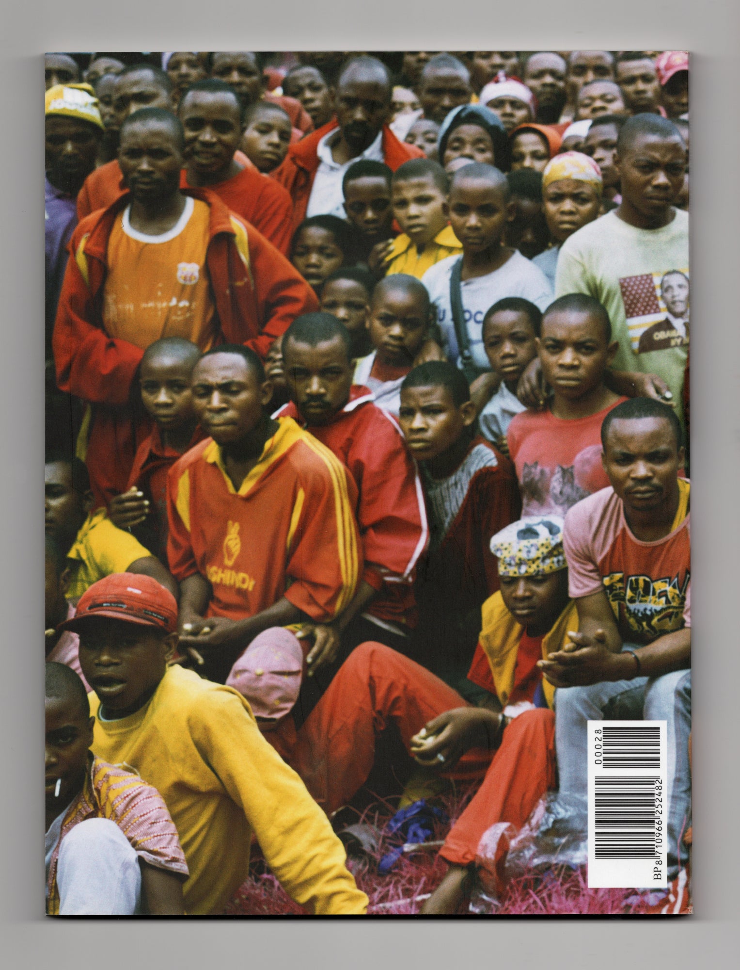 Achterkant GUP Magazine 028 The Conflict Issue uit februari 2011 met fotografie van politieagent in rood uniform met geweer in menigte van toeschouwers.
