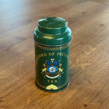 Vier theeblikjes van Jacksons of Piccadilly op een houten tafel, perfect voor thee liefhebbers.